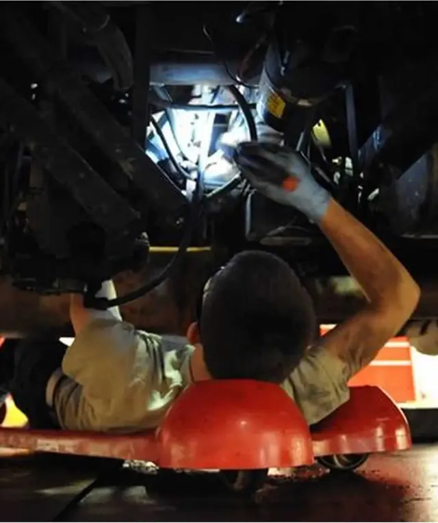 Technician working under a truck with a work light