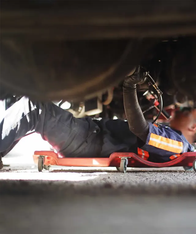 Technician on a creeper working under a trailer